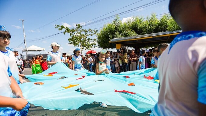 Desde as primeiras horas desta segunda-feira (7), os arredores da Orla de Juazeiro já recebiam um grande público para as comemorações do 7 de Setembro. Considerado uma das grandes tradições juazeirenses, o desfile cívico em celebração aos 204 anos da Independência do Brasil foi realizado pela Prefeitura de Juazeiro, por meio da Secretaria de Educação, e teve como tema “Juazeiro, Flor do São Francisco: Escrevendo uma história de pertencimento e sustentabilidade”. O evento teve a expectativa de reunir cerca de 40 mil pessoas, além da participação de mais de 7,4 mil estudantes e 36 instituições, entre escolas públicas e particulares e outras organizações. A programação começou às 7h30, no Paço Municipal, com o hasteamento das bandeiras, reunindo autoridades civis e militares, representantes dos poderes Executivo e Legislativo, forças de segurança e a comunidade. A bandeira do Brasil foi hasteada pelo tenente-coronel de França, comandante do 72º Batalhão de Infantaria de Caatinga; a da Bahia, pelo coronel PM Wildon Teixeira, comandante do Comando de Policiamento da Região Norte; e a de Juazeiro, pelo prefeito Andrei Gonçalves. Em seguida, ocorreu a revista das tropas e o desfile das forças militares, com a participação da Marinha do Brasil, Exército, Força Aérea Brasileira, Polícia Militar, Corpo de Bombeiros, Guarda Civil Municipal e Colégio da Polícia Militar Alfredo Viana. O desfile teve início na Avenida Aprígio Duarte, seguindo pela Rua Juvêncio Alves, Praça da Bandeira e Avenida Adolfo Viana. ——— MATÉRIA CONTINUA DEPOIS DA PUBLICIDADE ——— https://cafepingafogo.com.br/2022/ Entre os espectadores estava o casal formado pelo subtenente Marcos Fonseca e sua esposa, Ivete Fonseca, que mantém o hábito de prestigiar a celebração todos os anos. Para Marcos, a participação também representa uma oportunidade de reviver as memórias do período em que fazia parte das Forças Armadas. “Nesta manhã maravilhosa, relembro o período em que fazia parte das fileiras da ativa e, principalmente, revivo esse sentimento de patriotismo e de amor à nossa pátria. É uma alegria estar aqui mais uma vez, prestigiando esse grande espetáculo. A gente faz questão de participar todos os anos, porque é um momento único”, destacou. Após as corporações militares, teve início o desfile das escolas e instituições, que contou com a participação de 18 escolas, entre públicas e privadas, e mais de 22 fanfarras, sendo 8 da rede municipal. Com muito paetê, purpurina e brilho, os participantes levaram para a avenida alas relacionadas à temática deste ano, com referências ao Rio São Francisco, à história do município e a programas da gestão municipal, como o Juá Literária. Para a coordenadora da Escola Santa Inês, Regiane Lima, manter viva a tradição do desfile também é uma oportunidade de fortalecer o sentimento de pertencimento dos estudantes e compartilhar as produções desenvolvidas ao longo do ano letivo. “Trouxemos um pouquinho da nossa escola, ressaltando a importância do sentimento de pertencimento, tanto à cidade de Juazeiro quanto à nossa comunidade de Maniçoba. Também trabalhamos temas importantes, como a sustentabilidade e a valorização do esporte. A importância deste momento está justamente em sistematizar e compartilhar tudo aquilo que vem sendo trabalhado ao longo de todo o ano letivo, mostrando os projetos desenvolvidos pelos nossos estudantes”, afirmou. Além de prestigiar a criatividade apresentada pelas escolas, outro momento muito aguardado pelo público foi a participação das bandas e fanfarras da região. Neste ano, as bandas municipais receberam apoio da gestão municipal, com a entrega de oito novos kits de instrumentos musicais e fardamentos completos, fortalecendo a valorização dessa tradição cultural. Entre as bandas municipais que desfilaram pela avenida estavam as das escolas Terezinha Ferreira de Oliveira (BAMUSTER), Dinorah Albernaz (BAMAD), Anália Barbosa (BAMAB), 2 de Julho (BANDJ), Colégio CAIC (BANCAIC), Paulo VI (Fanfarra Paulo VI), Dom Avelar (Banda Marcial Dom Avelar) e Iracy Nunes (BAMIRY). Entre as fanfarras de destaque estava a da Escola Municipal de Tempo Integral Paulo VI. Tradicional nos desfiles cívicos de Juazeiro, neste ano a banda prestou homenagem a Charles Radson, ex-regente que faleceu no início deste ano e contribuiu para a consolidação da banda no município. O atual regente da Banda Marcial do Paulo VI, Rogério Santos, destacou a importância dos investimentos realizados pelo município e lembrou o legado deixado por Charles. “É importante destacar que a atual gestão tem dado uma grande contribuição para esse trabalho, principalmente com o investimento em instrumentos musicais e na ampliação das bandas, fazendo com que o trabalho esteja cada vez mais voltado para o aspecto pedagógico e didático, utilizando a música como ferramenta de formação para os nossos estudantes. Eu imagino que, se o Charles estivesse aqui neste momento, estaria muito feliz e satisfeito em ver tudo isso acontecendo. E nós temos a responsabilidade de dar continuidade a esse trabalho, mantendo viva essa história e fortalecendo cada vez mais a banda”, ressaltou. Com o tema “Juazeiro, Flor do São Francisco: Escrevendo uma história de pertencimento e sustentabilidade”, a gestão municipal relacionou a identidade de Juazeiro à preservação da cidade e do Rio São Francisco, reforçando que valorizar o lugar onde se vive também significa cuidar dele. Para a secretária de Educação, Maéve Melo, o tema deste ano reforçou a valorização da cultura local e o envolvimento da comunidade na celebração. Ela também destacou a adesão ao desfile e a participação das escolas e instituições. “É um tema que vem valorizar cada vez mais a nossa cultura juazeirense. Este ano tivemos uma maior adesão, com mais de 7,4 mil pessoas participando do desfile e 36 instituições. Estamos muito felizes porque o desfile superou as expectativas, principalmente pela participação de toda a cultura juazeirense”, destacou. : Maria Clara Oliveira – Ascom/PMJ Fotos: Anamauê – Ascom/PMJ